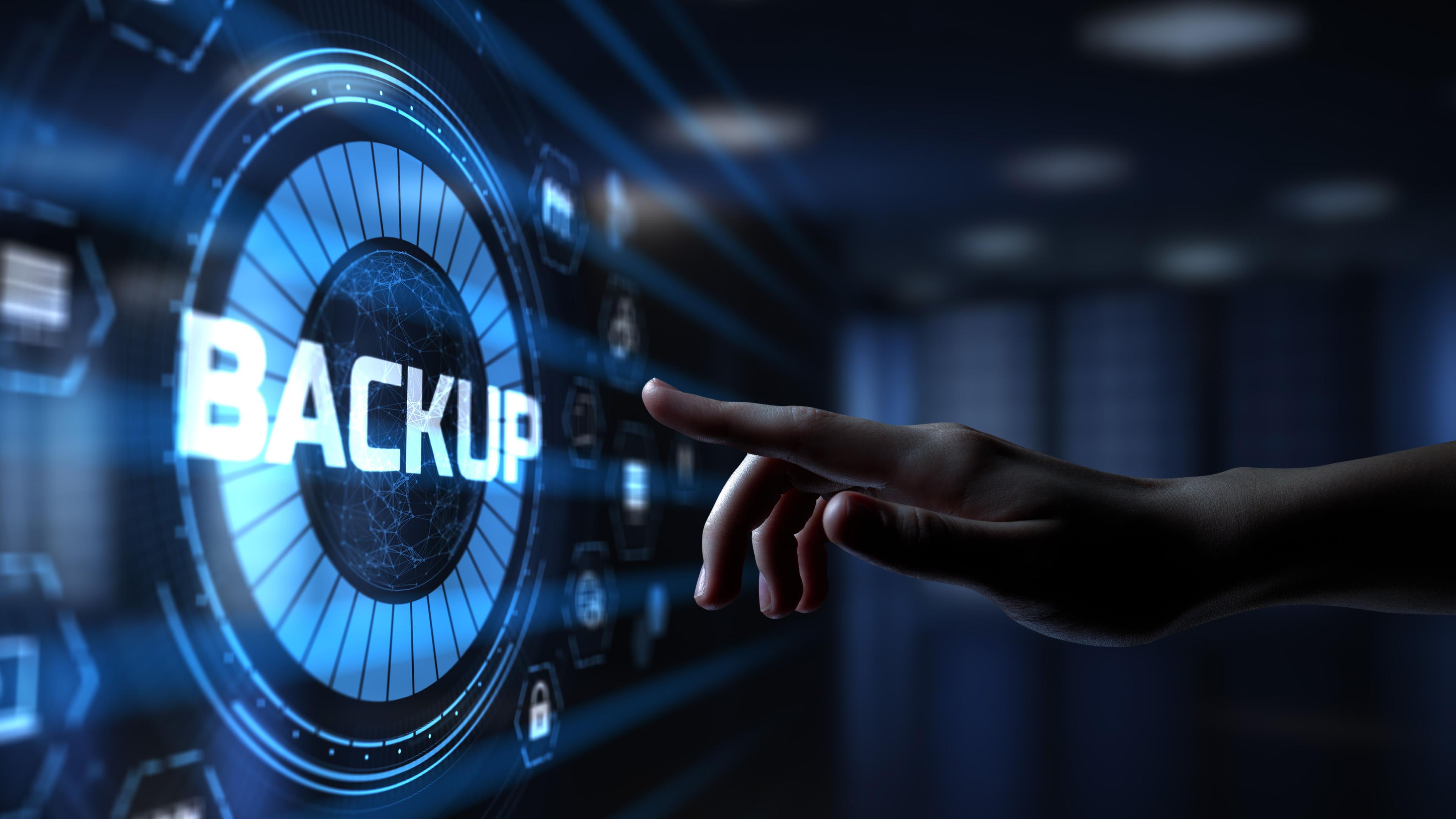 A hand is reaching out to touch a digital interface displaying the word "BACKUP" in large letters. The background features a futuristic, blue-toned digital environment with various icons and symbols, suggesting data storage  themes.